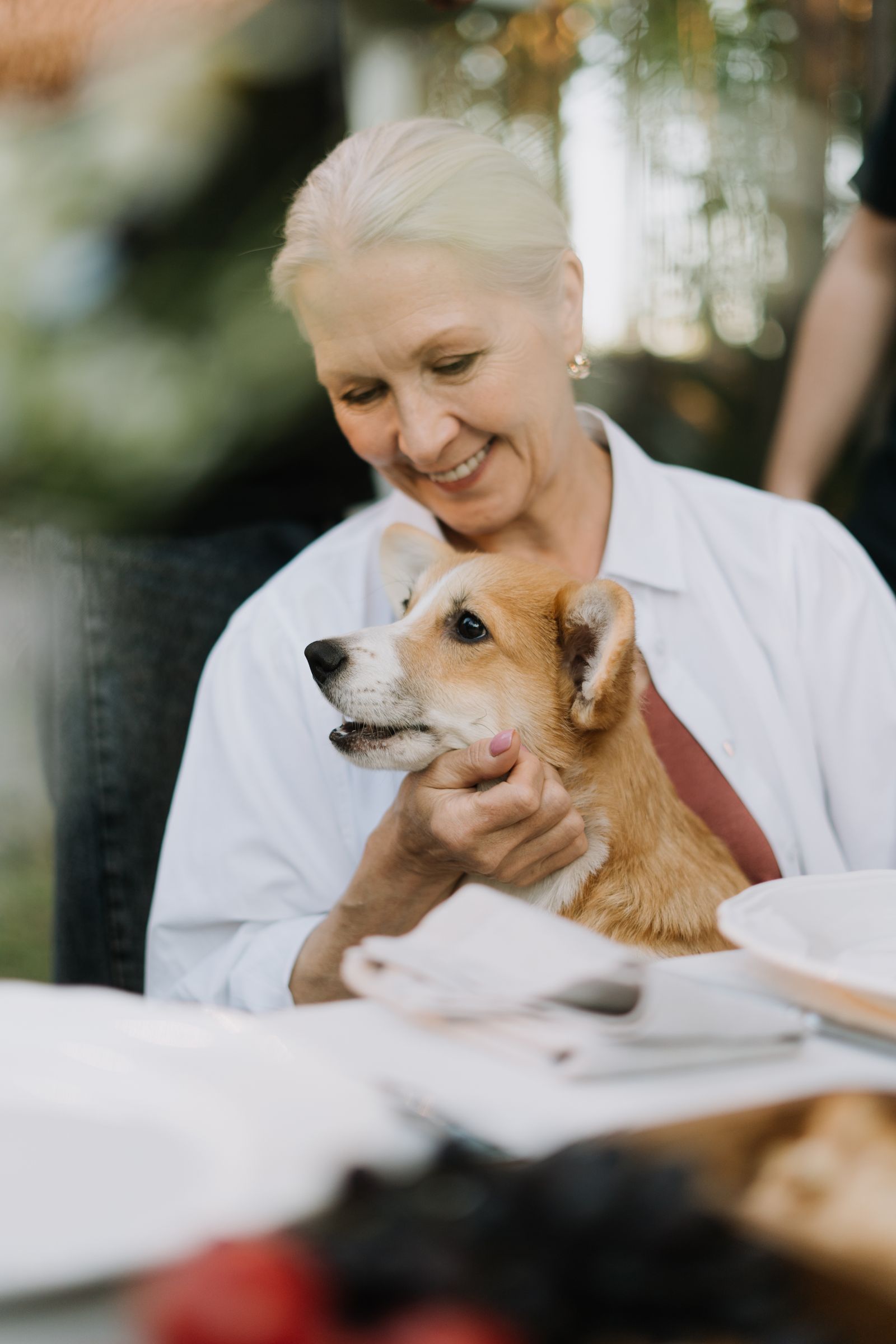 Aînée souriante caressant un petit chien lors d'une visite de zoothérapie