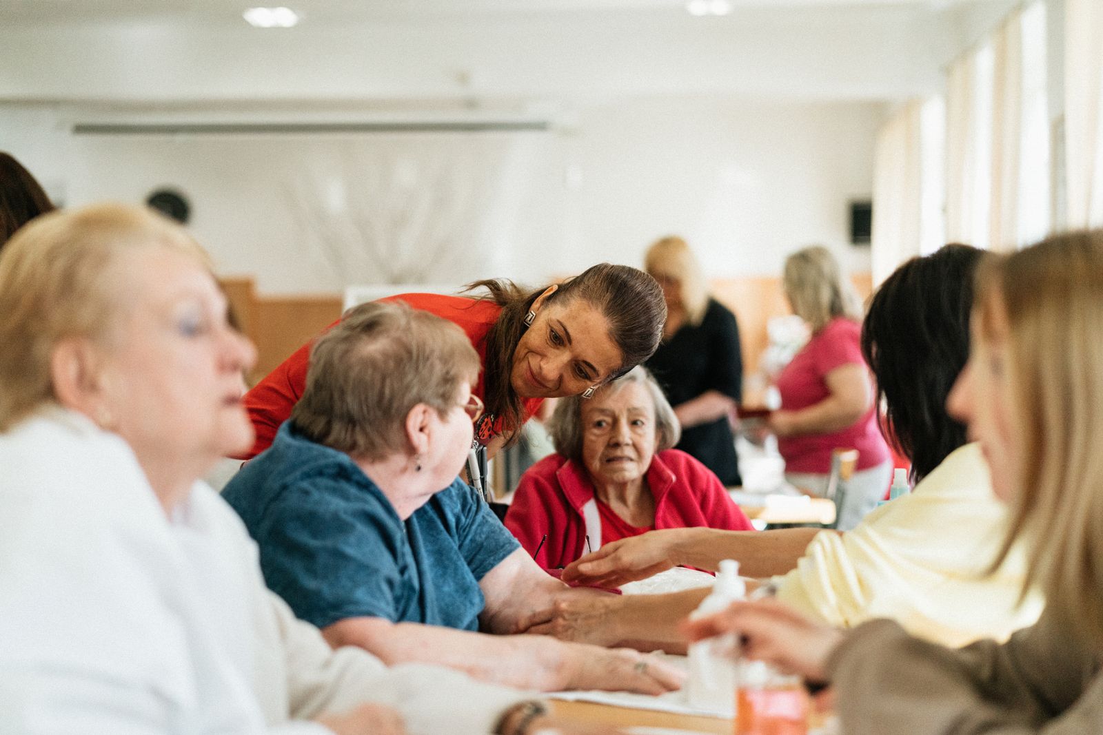 Une intervenante souriante échange avec un groupe de résidents autour d'une table